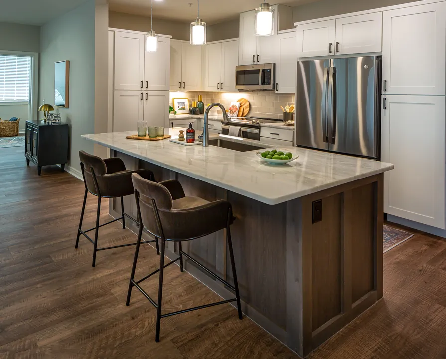 Kitchen space with a large refrigerator, microwave and oven, and a large island with a sink and bar seating